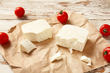 Tasty feta cheese with tomato on table
