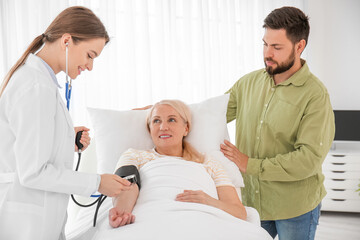 Mature woman with doctor and son in hospital room