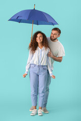 Happy young couple with umbrella on color background