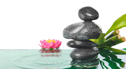 Spa stones, bamboo and flower in water against white background