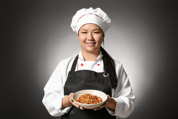 Beautiful Asian chef with dish on dark background