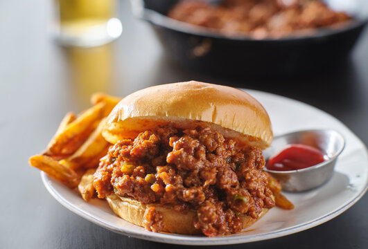 sloppy joe sandwich on plate with french fries and ketchup