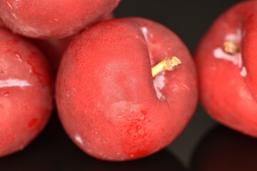 Ripe juicy, organic red plum, close-up, on a black background.