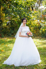 Portrait of a lonely bride on a background of an autumn park.