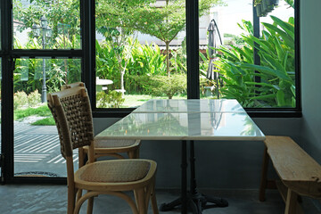 Interior design and decoration of coffee cafe and restaurant decorated with wooden furniture and mirror glass frame with green garden view