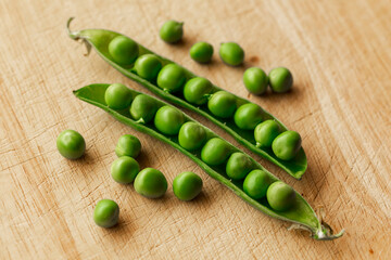 Green fresh pea pods and peas on wooden background, top view
