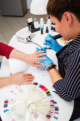 Nail salon, hands of client and master close-up. Nail treatment with a cutter