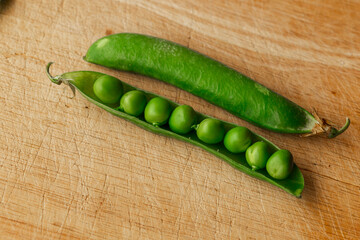 Green fresh pea pods and peas on wooden background, top view