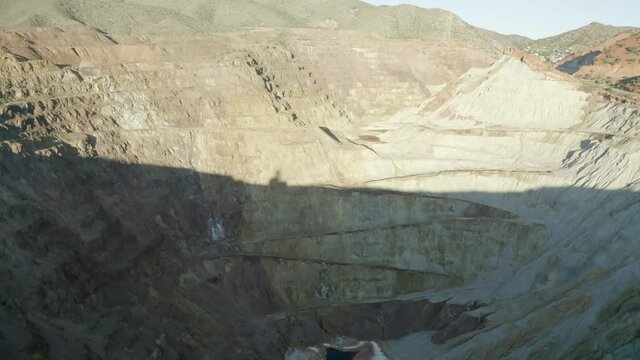 Aerial shot of abandoned open-pit copper mine on sunny day, drone flying backward over quarry - Bisbee, Arizona