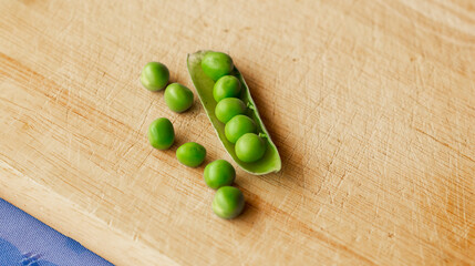 Green fresh pea pods and peas on wooden background, top view