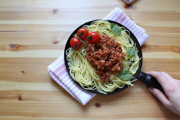 pasta with Basil tomato sauce and minced meat, serving spaghetti in a pan on a wooden background