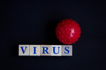 The inscription VIRUS from wooden cubes and the model of the strain of the virus. Black background.