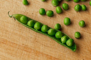 Green fresh pea pods and peas on wooden background, top view