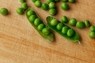 Green fresh pea pods and peas on wooden background, top view