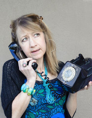 Angry mature woman engages in a serious conversation on her vintage dial phone.