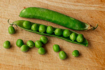 Green fresh pea pods and peas on wooden background, top view