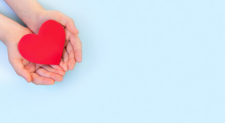 Obraz premium Children's hands hold red heart on a light background. ?oncept health care, organ donation, wellbeing, family insurance,love. World health day.National Organ Donor Day.World heart day.Banner