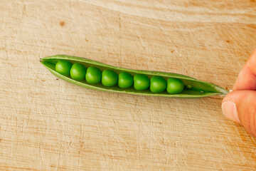 Green fresh pea pods and peas on wooden background, top view