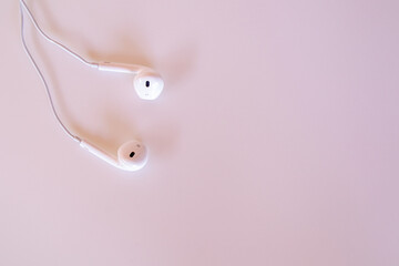 White headphones on pink background.