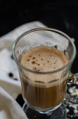 a cup of latte on a black background with pieces of white chocolate
