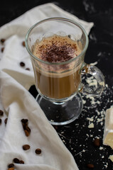 a cup of latte on a black background with pieces of white chocolate