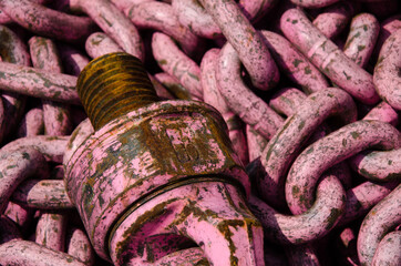 rosafarbene rostige Kette mit Gewinde in einem Schrottcontainer