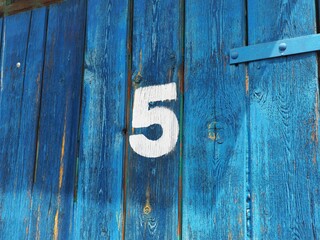 Number five on an old abandoned blue colour wooden gate in Budapest suburb, Hungary