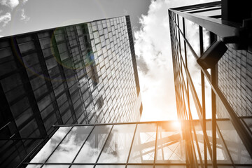 Facade texture of a glass mirrored office building. Fragment of the facade. Bottom view of modern skyscrapers in business district in evening light at sunset with lens flare filter effect. Black and w