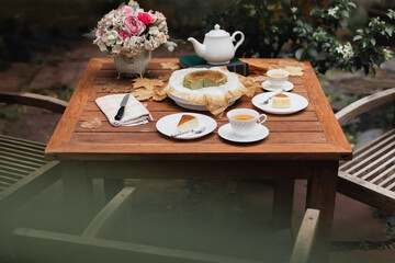 Afternoon tea basque burnt cheesecake and tea cup with teapot on wooden table.