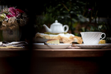 Afternoon tea basque burnt cheesecake and tea cup with teapot on wooden table.
