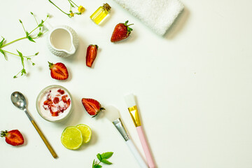 Fototapeta na wymiar Natural ingredients for a homemade strawberry mask for the skin. DIY Strawberry Face Mask. Top view on a white background strawberry, cream, lime slices, brushes, twigs of plants. Flat lay copy space