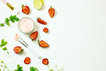 Natural ingredients for a homemade strawberry mask for the skin. DIY Strawberry Face Mask. Top view on a white background strawberry, cream, lime slices, brushes, twigs of plants. Flat lay copy space