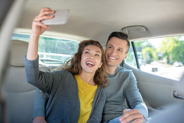 Woman taking a selfie with man in car