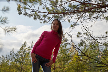 Beautiful young woman walking in the forest with sprice in autumn