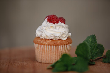 cupcake with frosting and raspberry. Muffin with cream and raspberry with mint near.