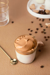 Glass of tasty dalgona coffee on color background