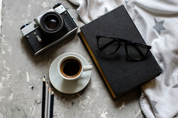 old camera on the table with a cup of coffee, a book and glasses