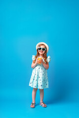 cute little girl in a dress, hat and sunglasses poses on a pink background