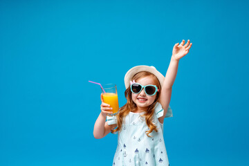 cute little girl in a dress, hat and sunglasses poses on a pink background