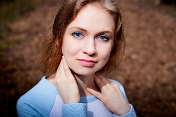 Fototapeta premium Portrait of cute blonde girl in blue dress outdoors. Nice woman posing on nature landscape.