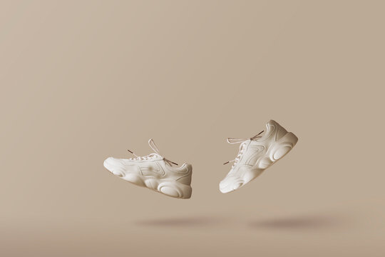 Modern women's sneakers of light color flying on a beige background. Stylish fashionable minimalism, concept levitation shoes, creative layout with copy space for text.