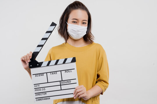 An Asian Woman Wearing A Mask Is Holding A Film Clapper Board. On A White Background.