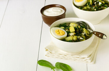 Green vegetable soup with sorrel leaves and eggs in a white bowl