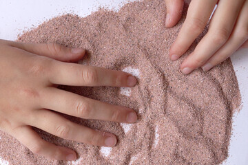 sand therapy, two hands draw with pink sand on a white table