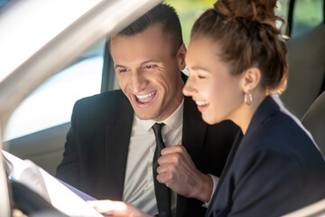 Satisfied man and woman with documents in a car