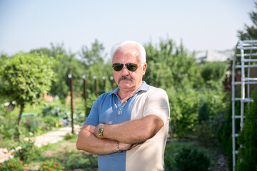 Senior grey-haired man in sunglasses in summer