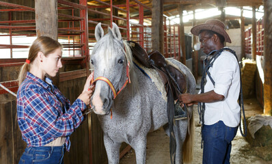 Farm workers preparing horse harness