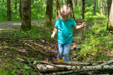 little girl walks through puddles in rubber boots in the forest