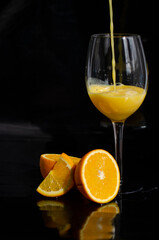 freshly squeezed orange juice on a black background with slices of orange