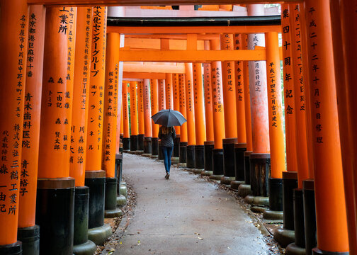 Woman walks through Fushimi Inari Shrine in Kyoto, Japan.  